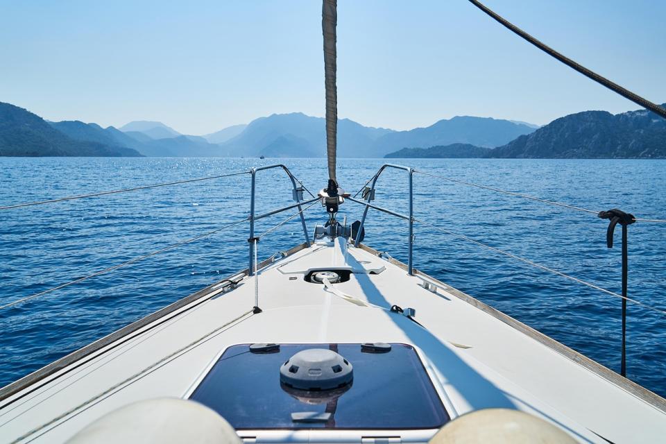 Blick über den Bug einer Segelyacht auf Berge und Meer